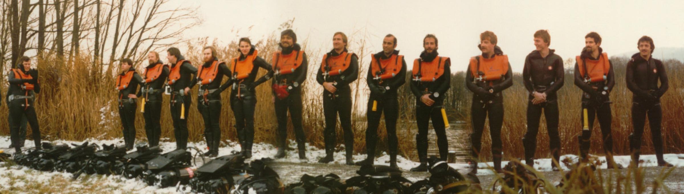 Tauchschwimmer im Tauchkombi, auf einem Glied versammelt