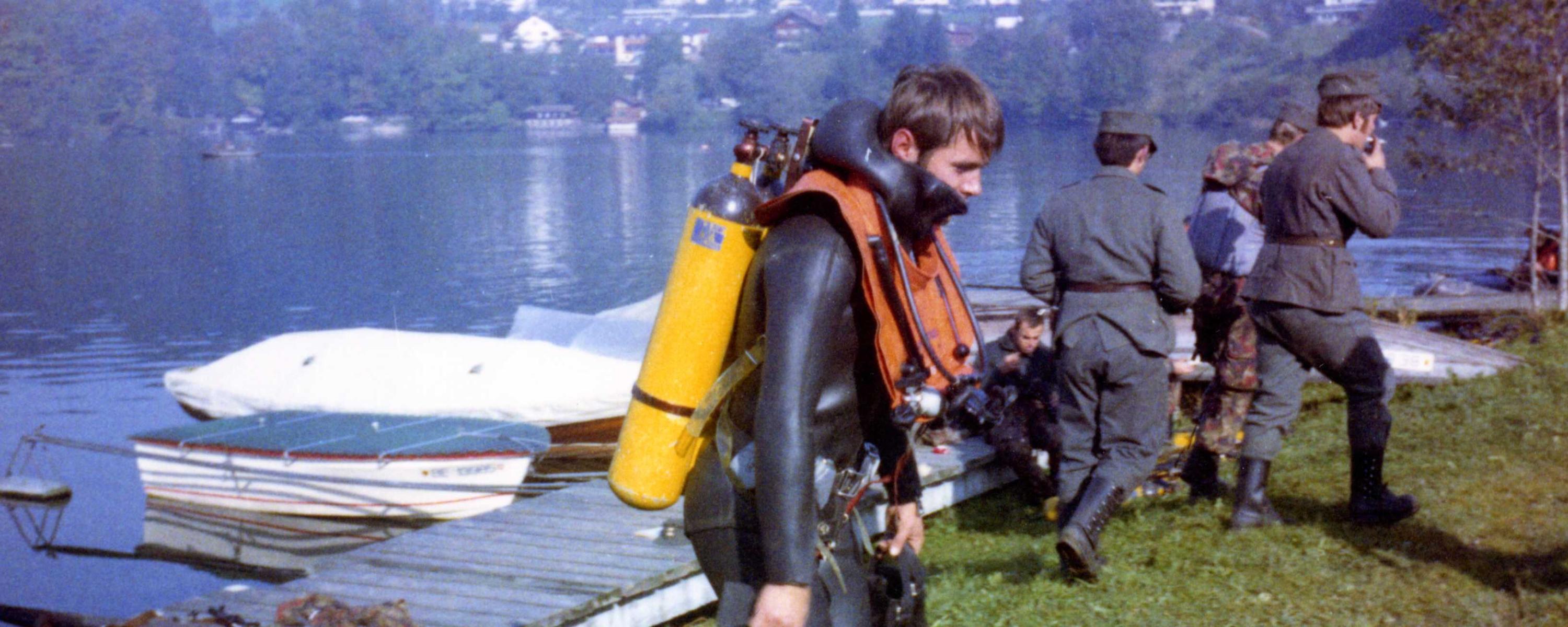Ein Taucher schleppt sich nach einem Tauchgang über den Rasen