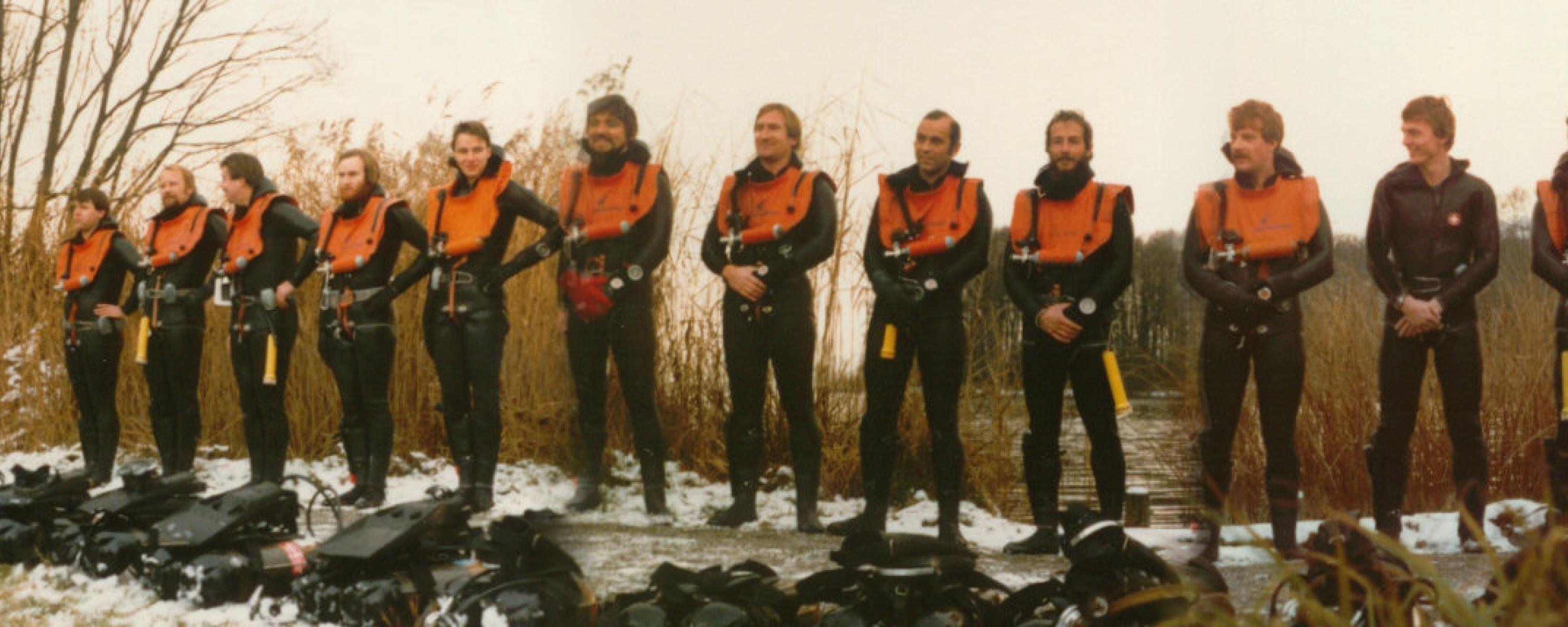 Tauchschwimmer im Tauchkombi, auf einem Glied versammelt